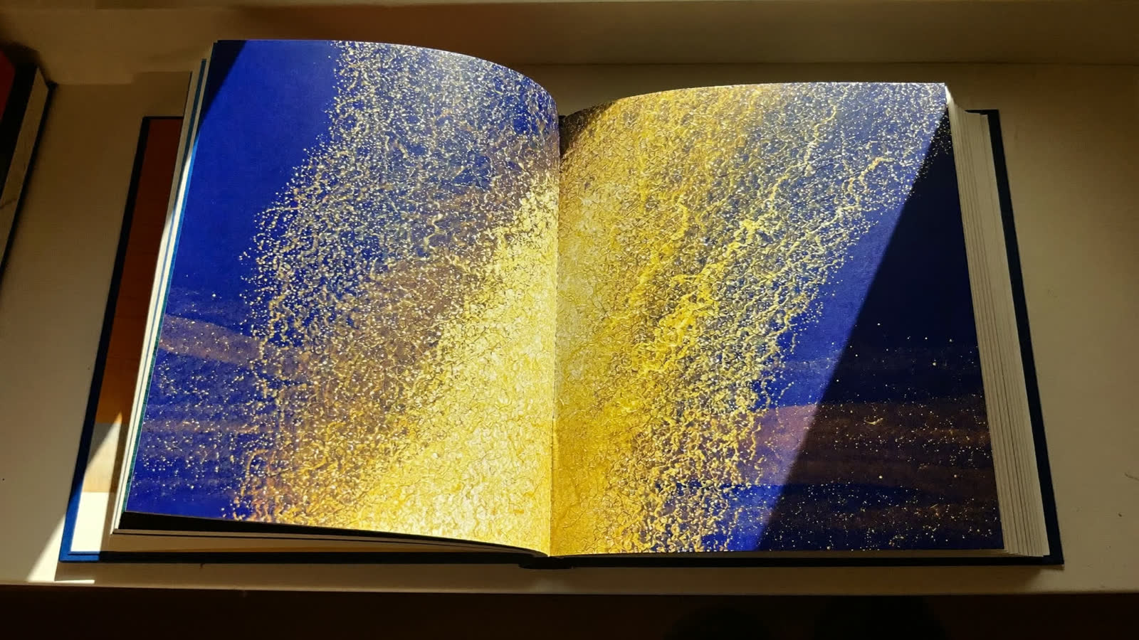 A golden spray of light rising from the pages of an open storybook, photographed against the dark.